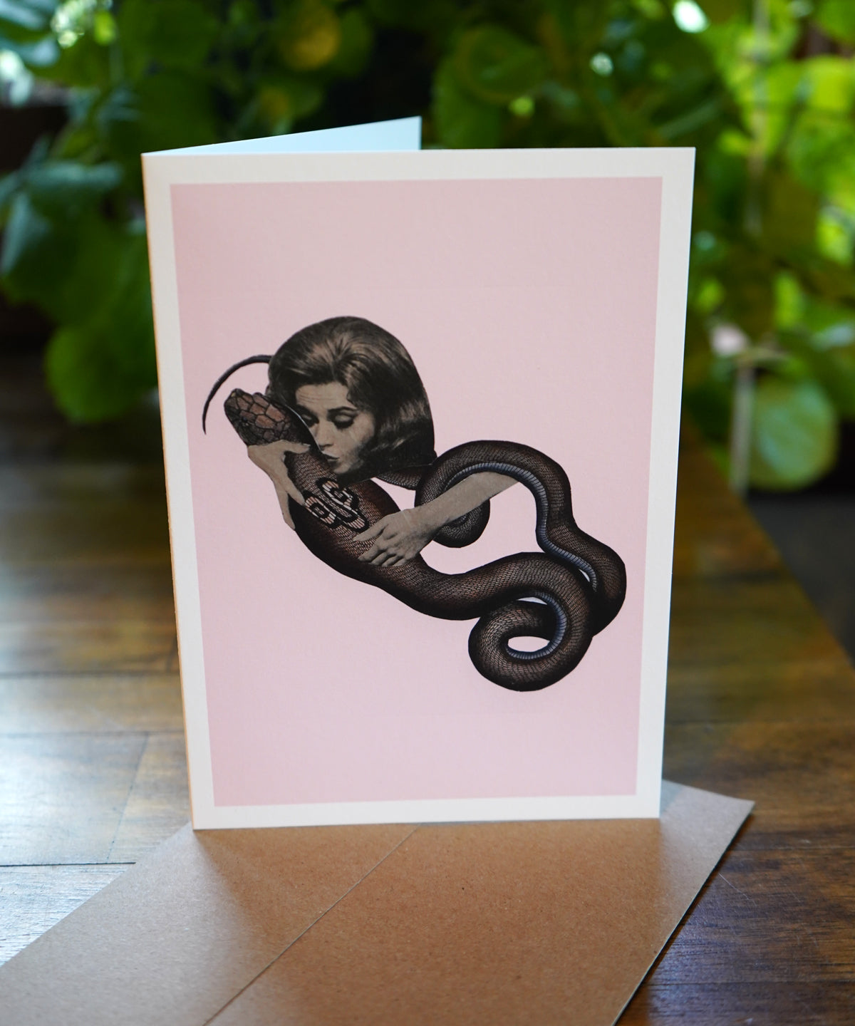 Greeting card with illustration of a woman holding a snake on a pink background