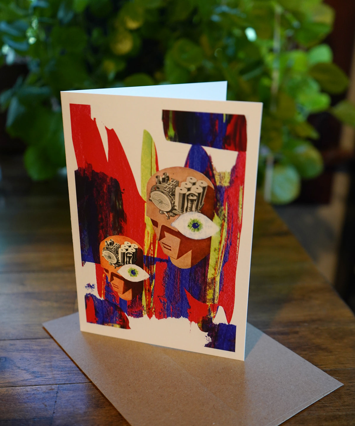 Colorful abstract art card on a wooden surface with a blurred green plant background