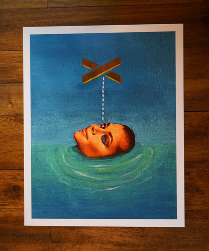 Art print of a head floating in water with an X above it on a wooden surface.