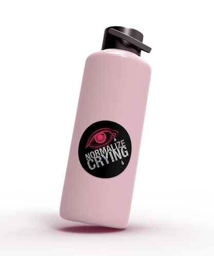 Pink water bottle with a black sticker featuring a crying eye and the text 'Normalize Crying'